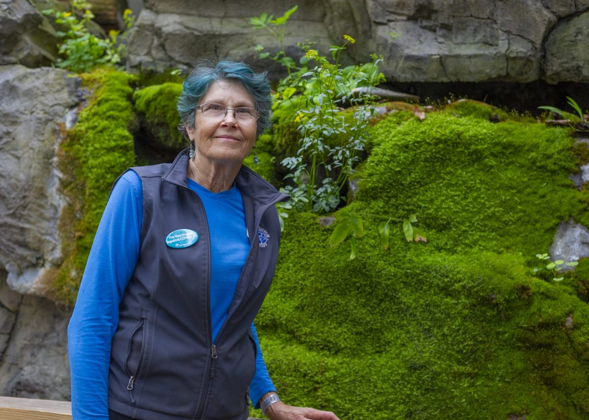 Lead Horticulturist Christine Hunt stands in front of a moss wallin the Appalachian Cove Forest gallery
