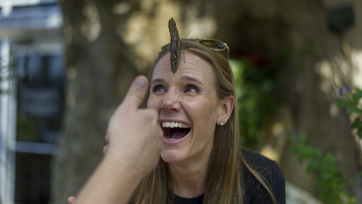 guest smiling as butterfly lands on her head