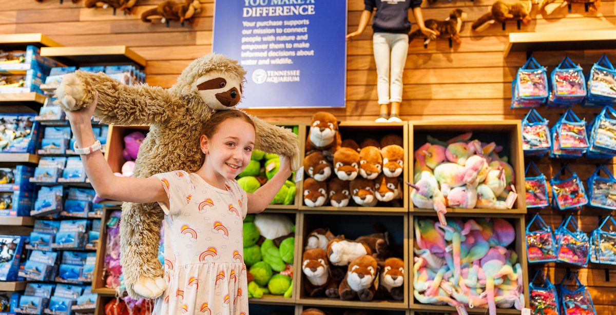 A girl holds a plush slot in the aquarium gift shop