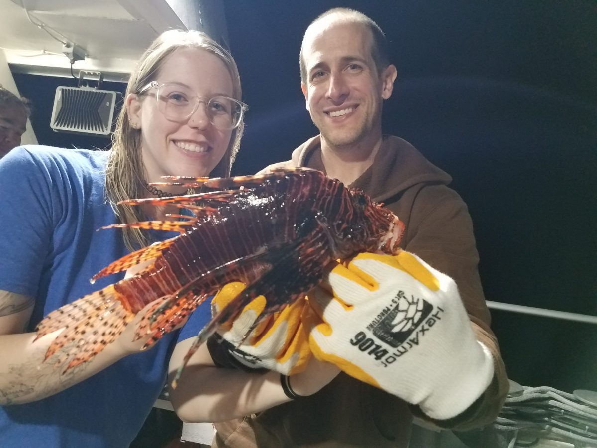 Two aquarists hold a Lionfish collected during the Lionfish Invitational