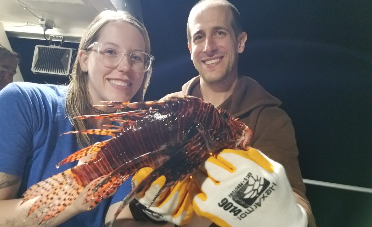 Two aquarists hold a Lionfish collected during the Lionfish Invitational