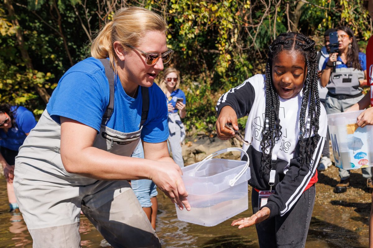 Reintroduction Assistant Hayley Martin helps a student from Girls Inc. of Chattanooga release a juvenile Lake Sturgeon into the Tennessee River.