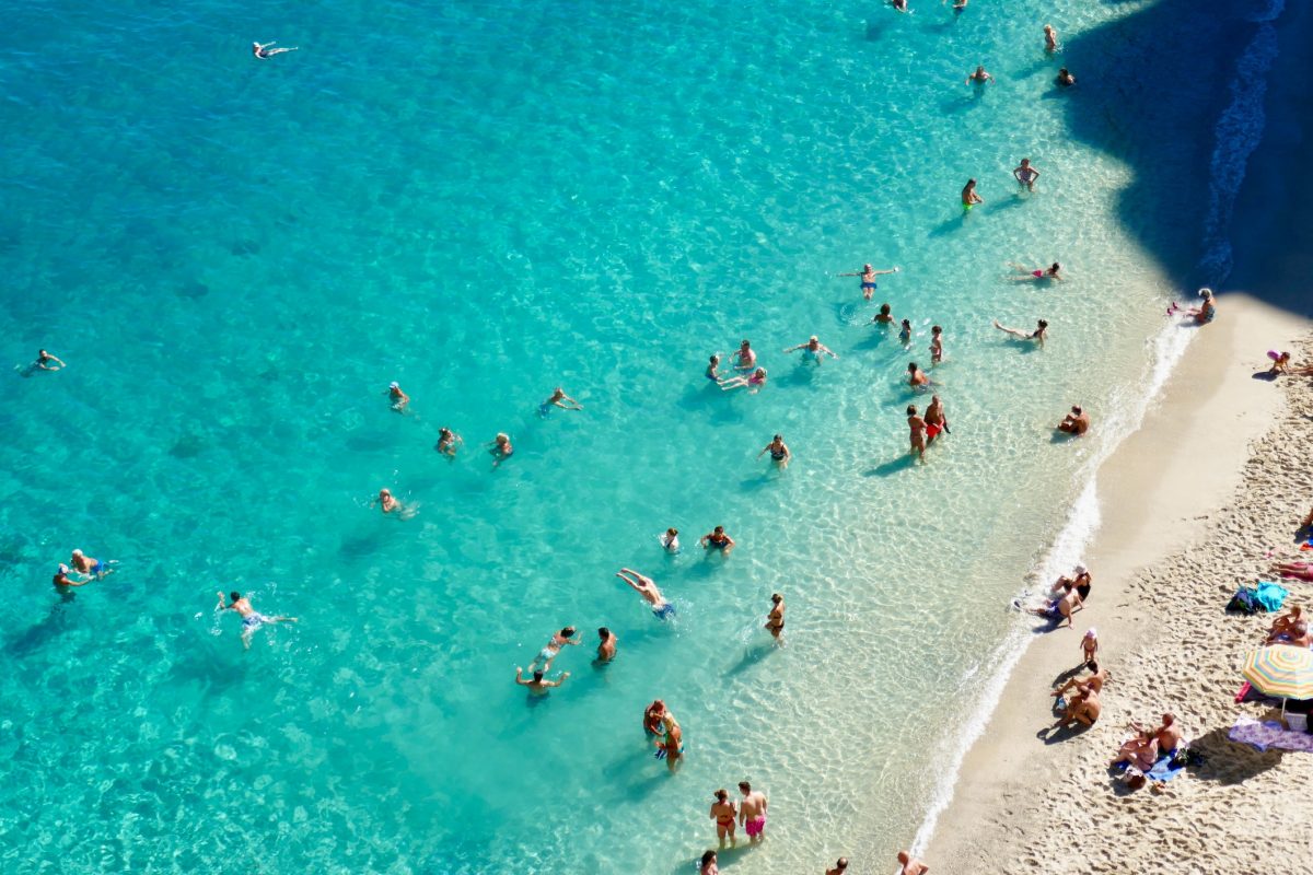 Bird's view of people bathing in crystal clear turquoise sea water at Rotonda beach in Tropea
