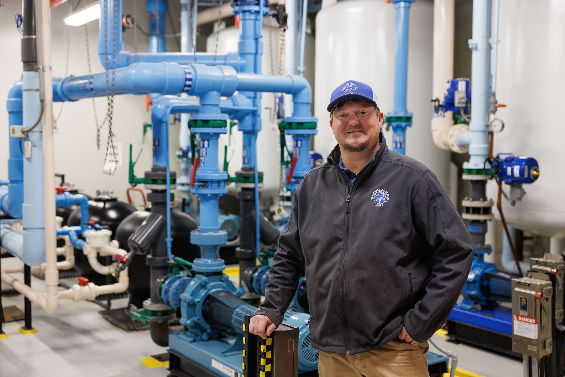 Plumbler Les Lawrence stands in room with aquarium pumps