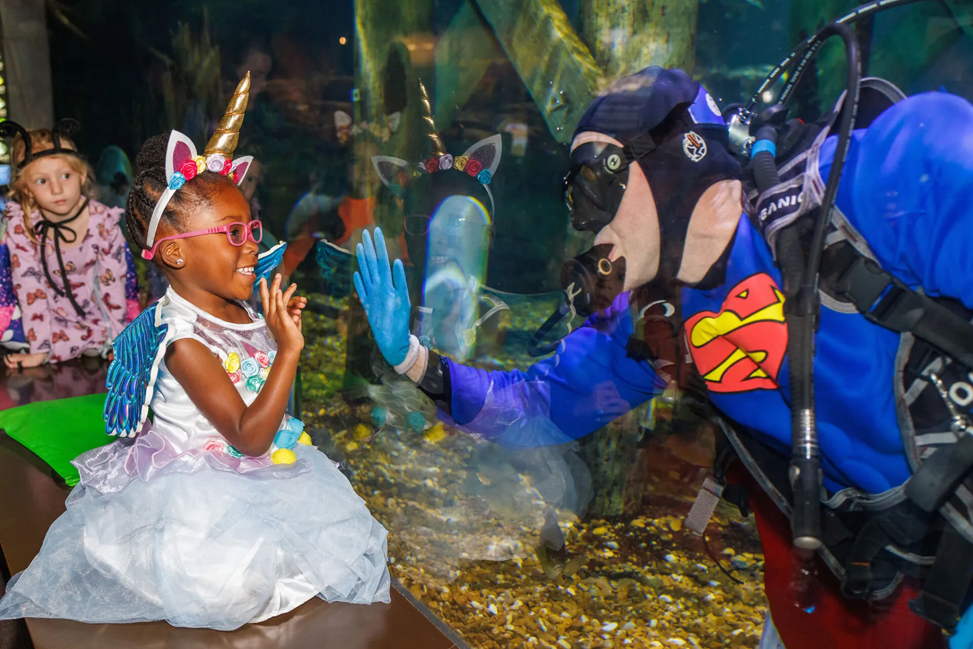 Child highfiving superman in dive tank