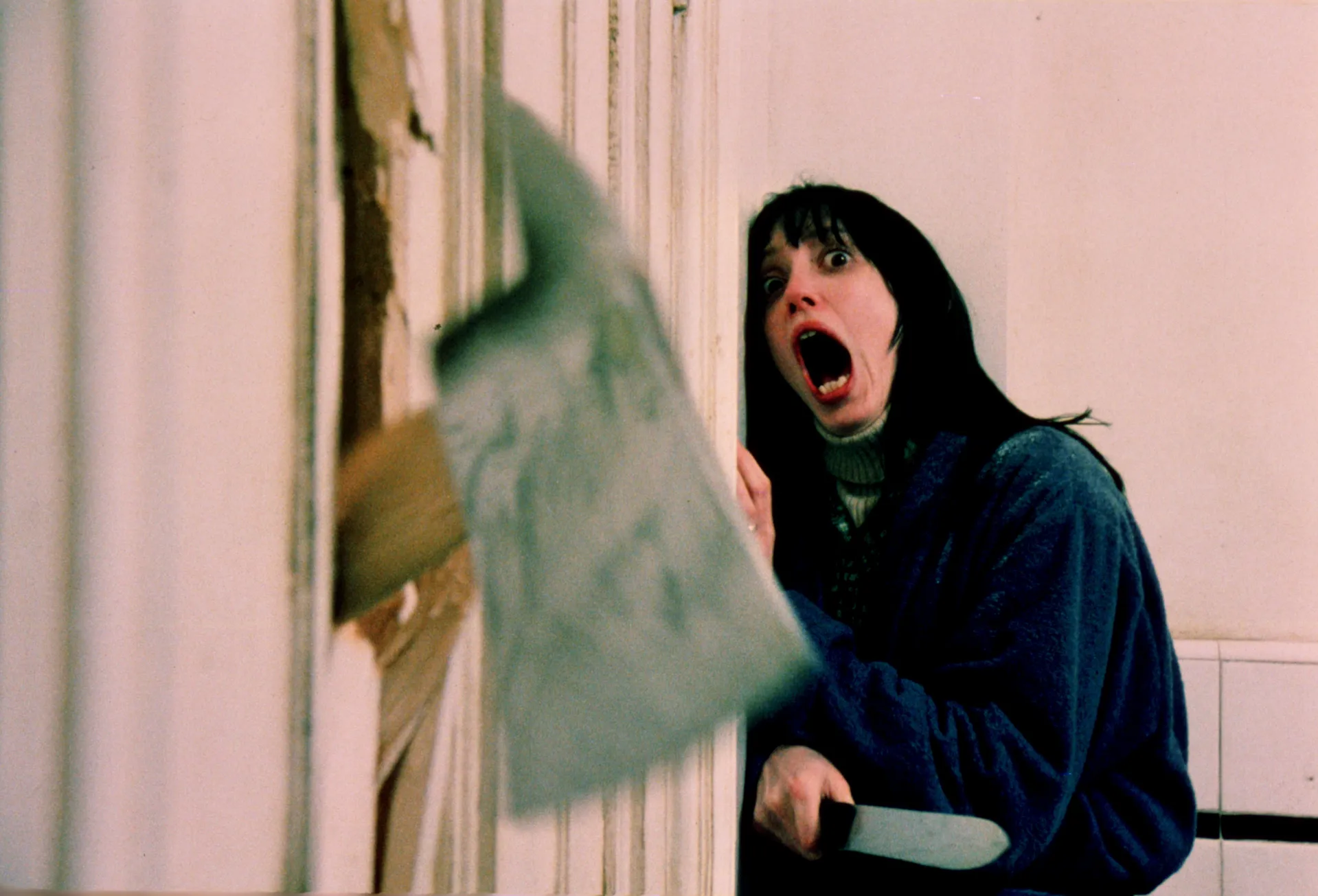 Actress Shelley Duvall in the Shining, appearing terrified, hiding behind a door from main character Jack Torrance (Nicholson)