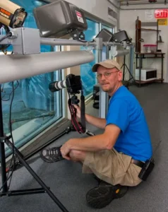 Todd Stailey poses with a camera and tripod outside the Penguins' Rock exhibit