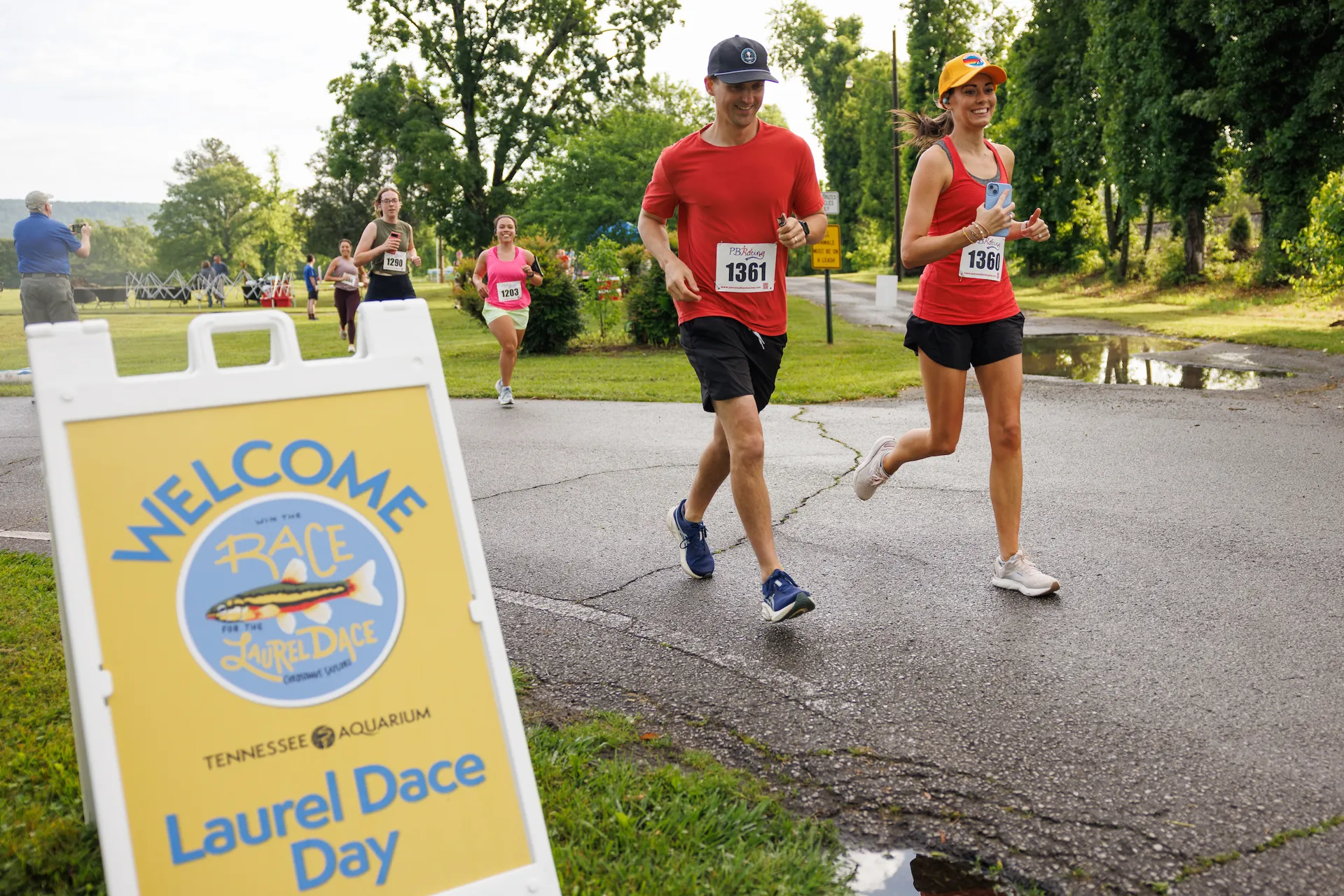 Laurel Dace Day welcome sign in the left and race participants running during Laurel Dace Day 2025