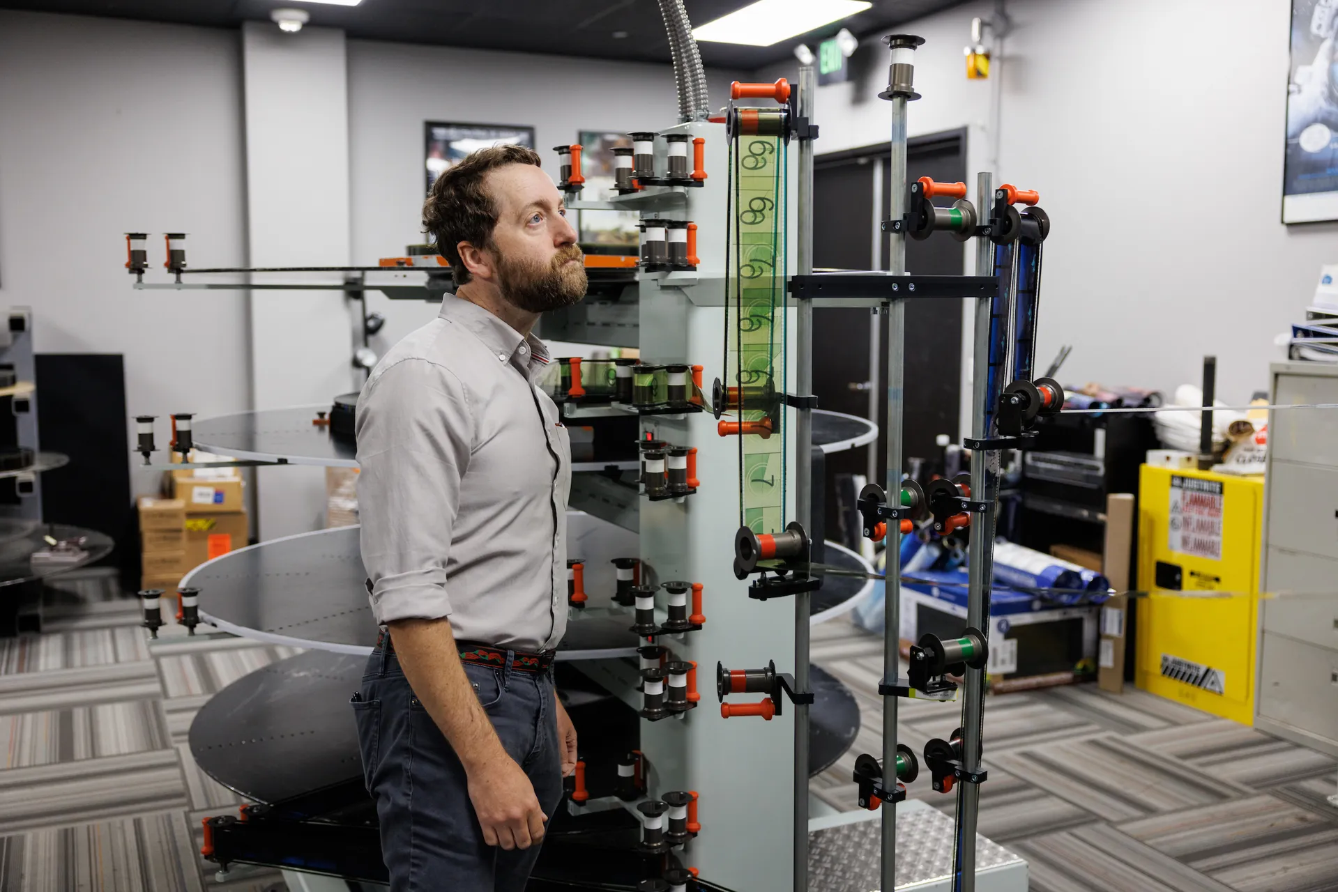 A man looks at a reel of film spooling in preparation for projection in a theater.